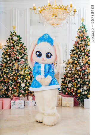 a bunny doll in a blue snow maiden costume in a room with Christmas trees.  96738433