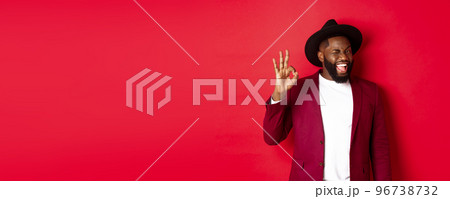 Christmas shopping and people concept. Handsome Black man showing ok sign with confidence, give guarantee, saying yes, standing over red background 96738732