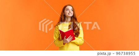 Dreamy, inspirational cute redhead female student writing daily tasks, to-do list in red lovely planner, look upper left corner thoughtful as smiling, getting inspiration to write novel, orange wall Dreamy, inspirational cute redhead female student writing daily tasks, to-do list in red lovely planner, look upper left corner thoughtful as smiling, getting inspiration to write novel, orange wall 96738955