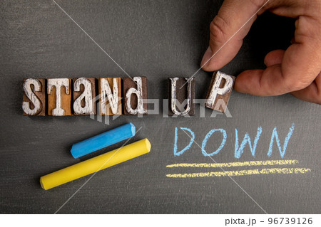 Stand Up and Stand Down. Wooden letter blocks on a dark chalkboard background 96739126