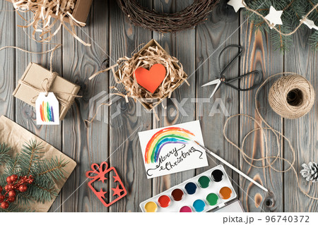 Watercolor rainbow postcard and handmade gift box in festive package, top view. Spruce branches and tools. Crafting present. Christmas holiday concept, LGBT symbol, homosexual orientation 96740372