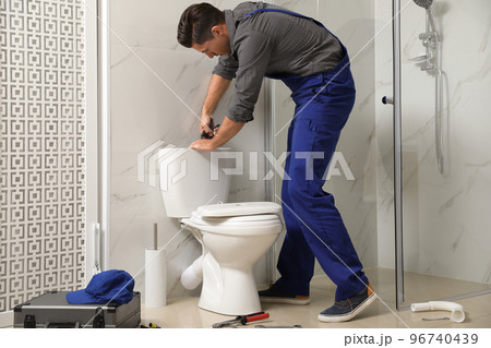 Professional plumber working with toilet bowl in bathroom 96740439