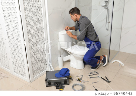 Professional plumber working with toilet bowl in bathroom 96740442
