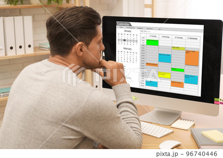 Handsome man using calendar app on computer in office Handsome man using calendar app on computer in office 96740446