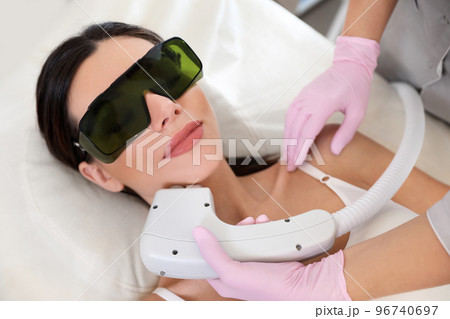 Young woman undergoing laser epilation procedure in beauty salon 96740697