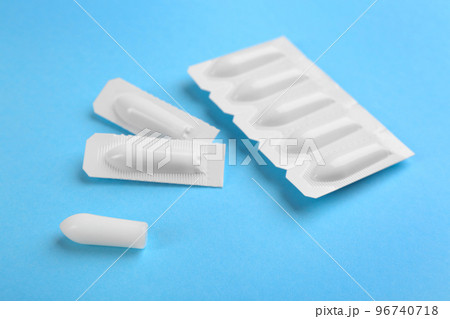 Suppositories on light blue background. Hemorrhoid treatment 96740718