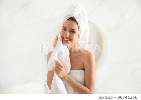 Young woman wiping face with towel in bathroom 96741266