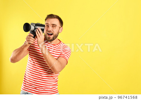 Young man with vintage video camera on yellow background, space for text Young man with vintage video camera on yellow background, space for text 96741568