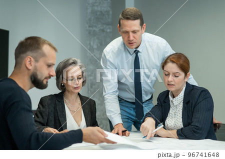 The boss gives instructions to three employees in the office conference room. Brainstorming engineers and architects. The boss gives instructions to three employees in the office conference room. Brainstorming engineers and architects. 96741648