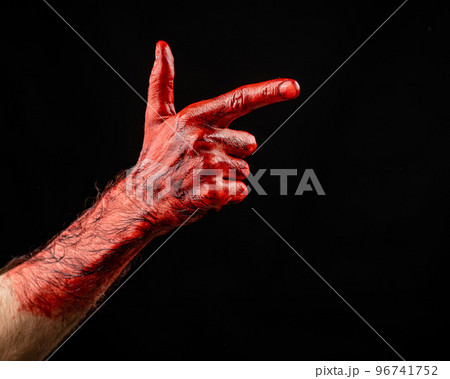 Bloody male hand gesturing shows a gun against black background. 96741752