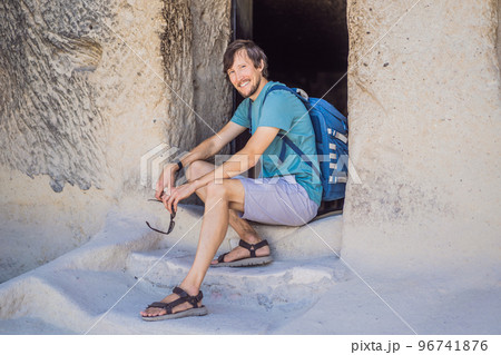 Young man exploring valley with rock formations and fairy caves near Goreme in Cappadocia Turkey Young man exploring valley with rock formations and fairy caves near Goreme in Cappadocia Turkey 96741876