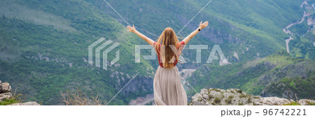 BANNER, LONG FORMAT Woman tourist on background of Blue river running through green valley toward distant mountains. Beautiful mountains of Montenegro and the river Cievna BANNER, LONG FORMAT Woman tourist on background of Blue river running through green valley toward distant mountains. Beautiful mountains of Montenegro and the river Cievna 96742221