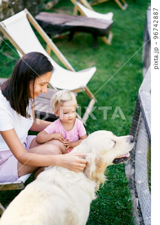 Mom and little girl petting a golden retriever. High quality photo Mom and little girl petting a golden retriever. High quality photo 96742887