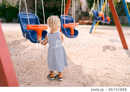 Little girl stands near the swing. Back view. High quality photo 96742888