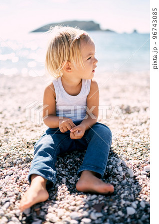 Little girl is sitting on a pebble beach. High quality photo Little girl is sitting on a pebble beach. High quality photo 96743085