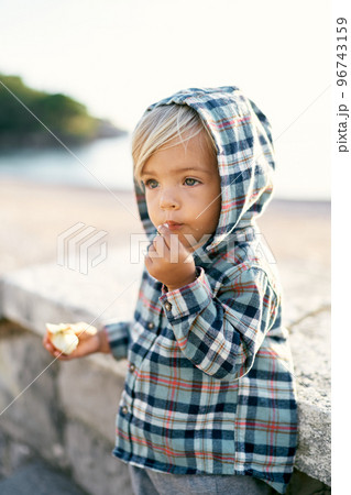 Little girl in a hooded shirt eating an apple on the stone steps. High quality photo Little girl in a hooded shirt eating an apple on the stone steps. High quality photo 96743159