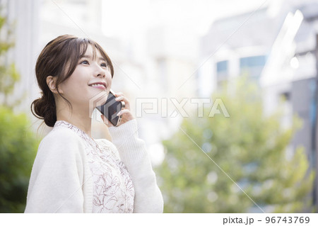 街角でスマホで通話をする若い女性 96743769