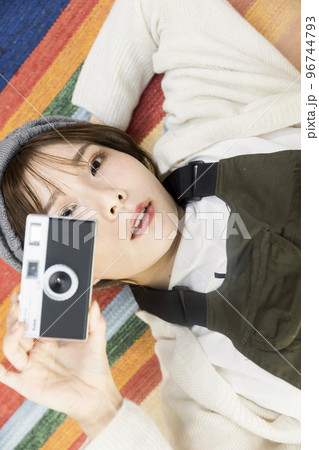 ラグマットに寝転んでフィルムカメラを持つ若い女性 ラグマットに寝転んでフィルムカメラを持つ若い女性 96744793
