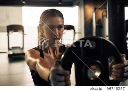 Sporty woman doing workout with weight plate at the gym. Sporty woman doing workout with weight plate at the gym. 96746277