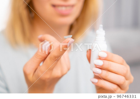 Woman holding contact lens on the finger and eye drop in her hand. Eyecare concept.  96746331