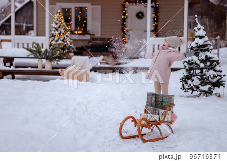 A girl is carrying an authentic wooden sleigh with gifts 96746374