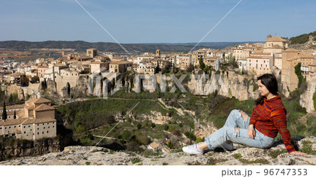 Woman tourist sitting on hill, Cuenca, Spain Woman tourist sitting on hill, Cuenca, Spain 96747353