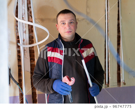 Electrician with cable duct in hands looking at camera 96747775