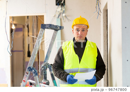 Male contractor looking at room and determining scope of building work 96747800