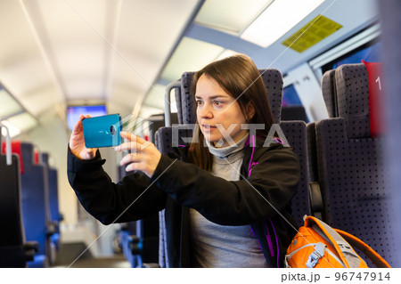 Woman photographing view from train window Woman photographing view from train window 96747914