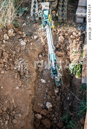 Mini excavator digs a trench to lay pipes. Close up of an excavator digging a deep trench. An excavator digs a trench in the countryside to lay a water pipe. Slow motion Mini excavator digs a trench to lay pipes. Close up of an excavator digging a deep trench. An excavator digs a trench in the countryside to lay a water pipe. Slow motion 96748414
