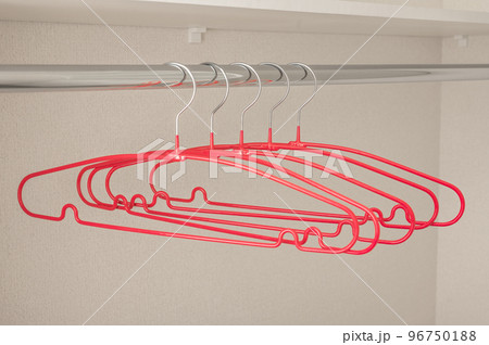 Many pink hangers on rod, grey wall background. Store concept, sale, design, empty hanger. Clothes hangers in empty wardrobe 96750188
