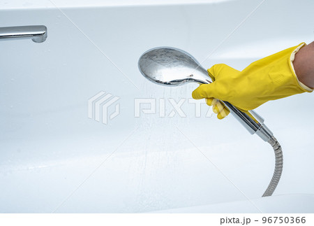 Person using hand held shower head. gloved hand holding shower head. hand holds shower head with pouring water 96750366