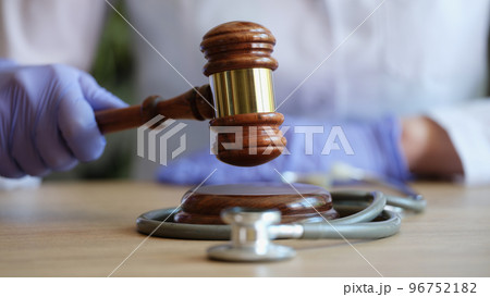 Doctor holds judge gavel in gloved hands close up. 96752182