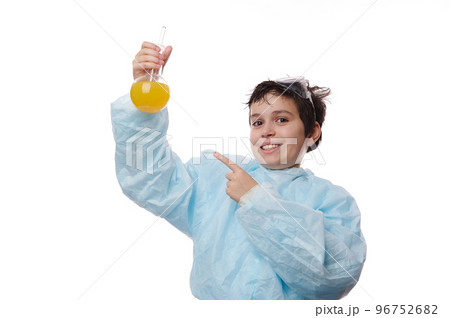 Handsome smart teenage boy in lab coat, points with index finger at a glass laboratory flask with chemical solution, conducting scientific experiments at chemistry class, isolated on white background Handsome smart teenage boy in lab coat, points with index finger at a glass laboratory flask with chemical solution, conducting scientific experiments at chemistry class, isolated on white background 96752682