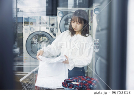 コインランドリーで洗濯物をたたむ若い女性 コインランドリーで洗濯物をたたむ若い女性 96752818