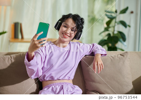 Smiling teenage girl listening to music in s and taking selfie Smiling teenage girl listening to music in s and taking selfie 96753544