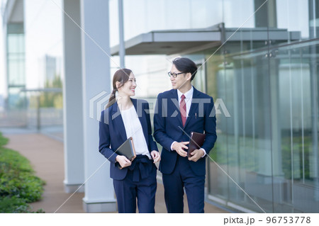 研究開発センターをスーツ姿で歩く男女 96753778