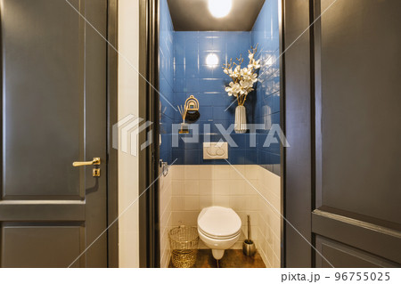 Interior of narrow restroom with wall hung toilet with white walls and checkered floor 96755025
