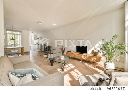 Contemporary open plan kitchen with dining table set and gray sofa in light spacious room 96755037