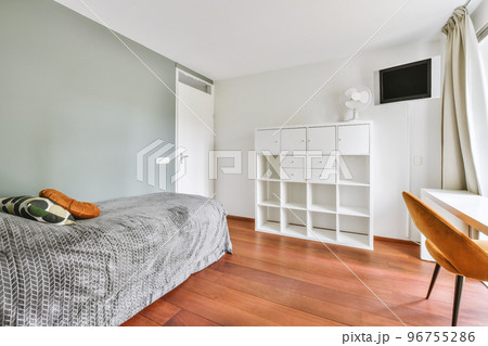 Home interior design of bedroom with bed and wooden wardrobe placed in corner near window in modern apartment 96755286