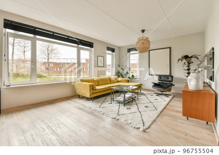 Modern minimalist style interior design of studio apartment with open white kitchen and dining zone with table and chairs illuminated by loft style lamp 96755504