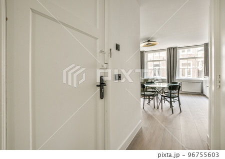 Light narrow hallway with many doors in white walls and glowing lamp over lumber floor 96755603