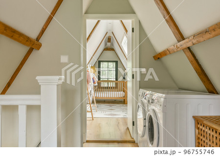 Washing machines placed near stairs in bright mansard room 96755746