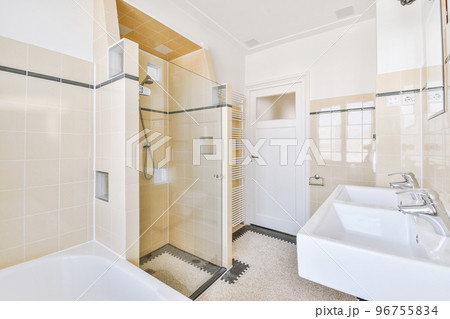 Spacious bathroom with stone sink and mirror on black and white colored tiled wall in expensive apartment 96755834