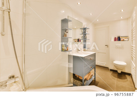Sinks with mirrors and clean bathtub located near shower box with glass door in modern bathroom with white tiled walls Sinks with mirrors and clean bathtub located near shower box with glass door in modern bathroom with white tiled walls 96755887