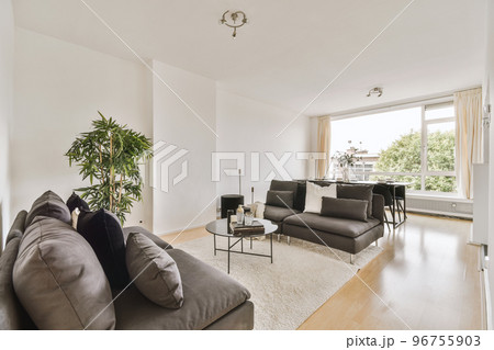 Contemporary minimalist style interior design of light studio apartment with wooden table and chairs in dining zone between open kitchen and living room with white walls and parquet floor Contemporary minimalist style interior design of light studio apartment with wooden table and chairs in dining zone between open kitchen and living room with white walls and parquet floor 96755903