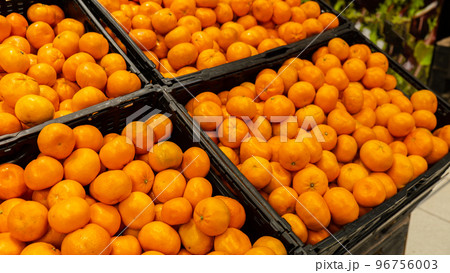 Showcase with range of fruits in supermarket. Sale of food. Retail. Fresh oranges, tangerines and lemons stored on shelves. Exotic fruits. Ripe and healthy fruits. Concept of supermarket purchases of 96756003