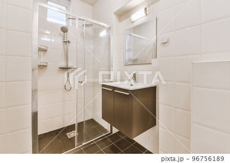 Flush toilet located between sink and shower in small tiled bathroom of contemporary apartment Flush toilet located between sink and shower in small tiled bathroom of contemporary apartment 96756189