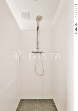 Modern flush toilet and ceramic sink installed on white tiled walls near mirror and towel in small restroom at home 96756574