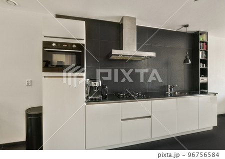 Table with chairs and flowers located near lounge area and kitchen in spacious room of contemporary apartment 96756584